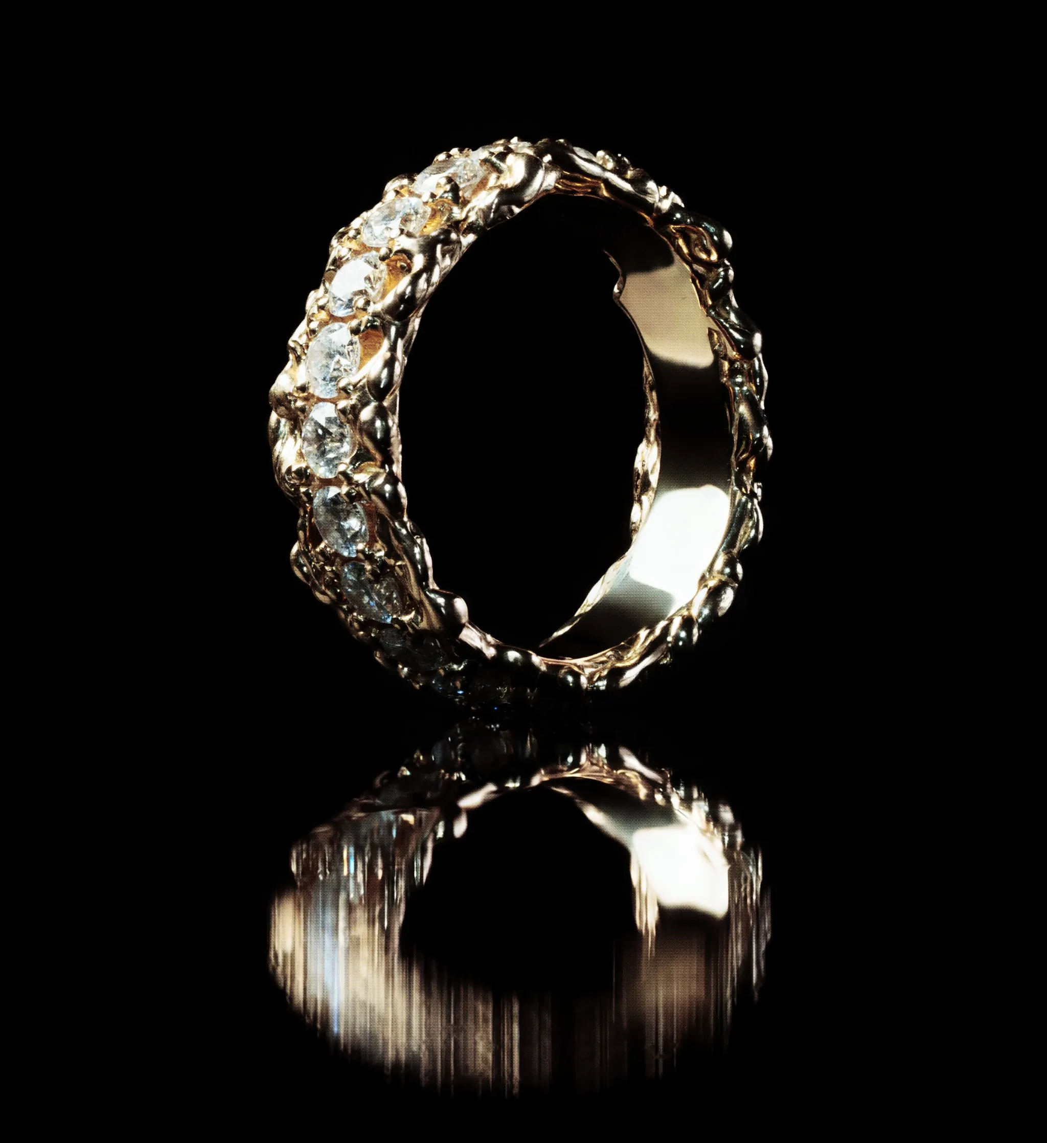 Yellow gold eternity band with an organic, lava-like surface, set all around with brilliant-cut diamonds and mirrored on a black surface